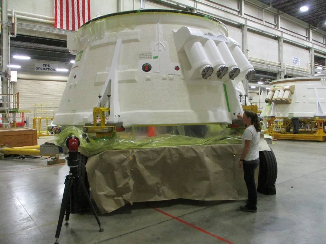 Aerospace technician measuring a spacecraft module with a laser tracker for assembly alignment verification